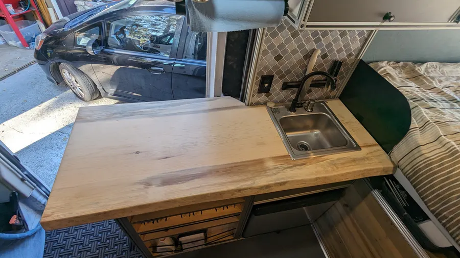 Live-edge butcher block galley with stainless sink — Big Bear Camper Vans build
